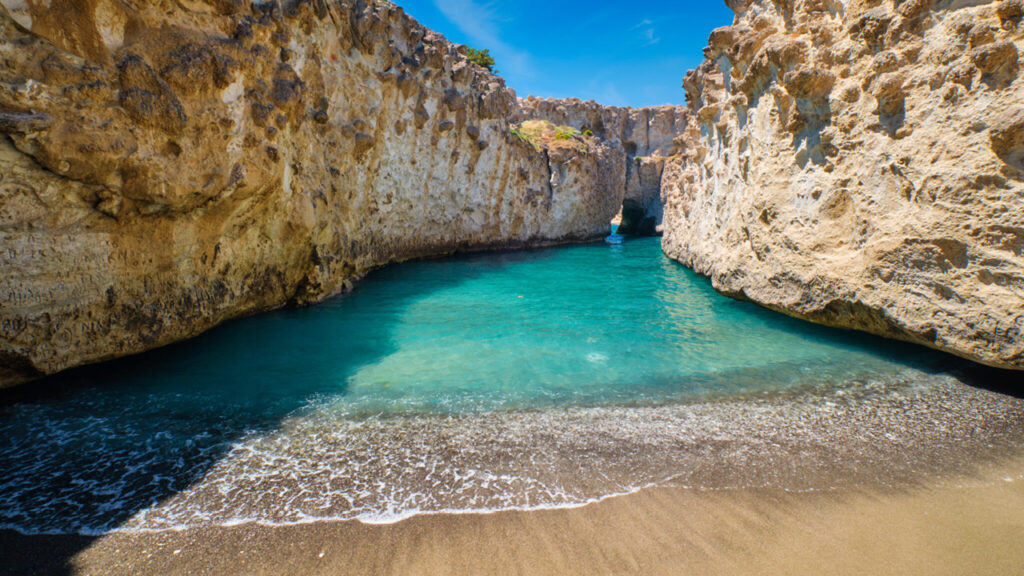 View of a small, secluded beach with small cliffs on either side on the island of Milos