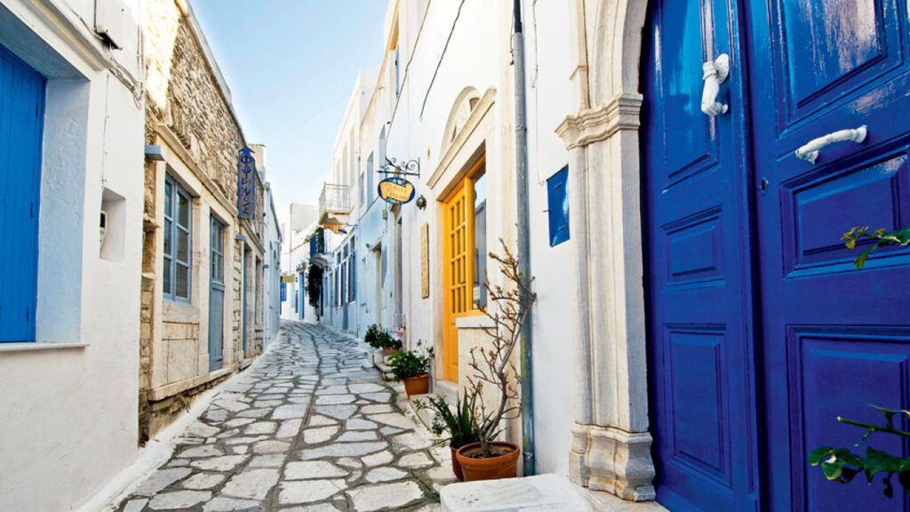 View of an alley in Tinos with multi-colored door and window frames.