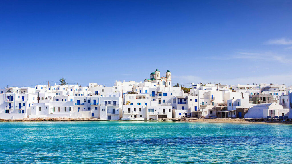 A view of pristine white buildings on the water, in Paros